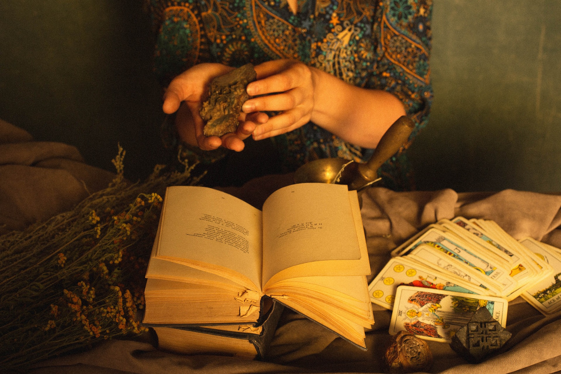 books, a deck of tarot cards, and herbs on a table